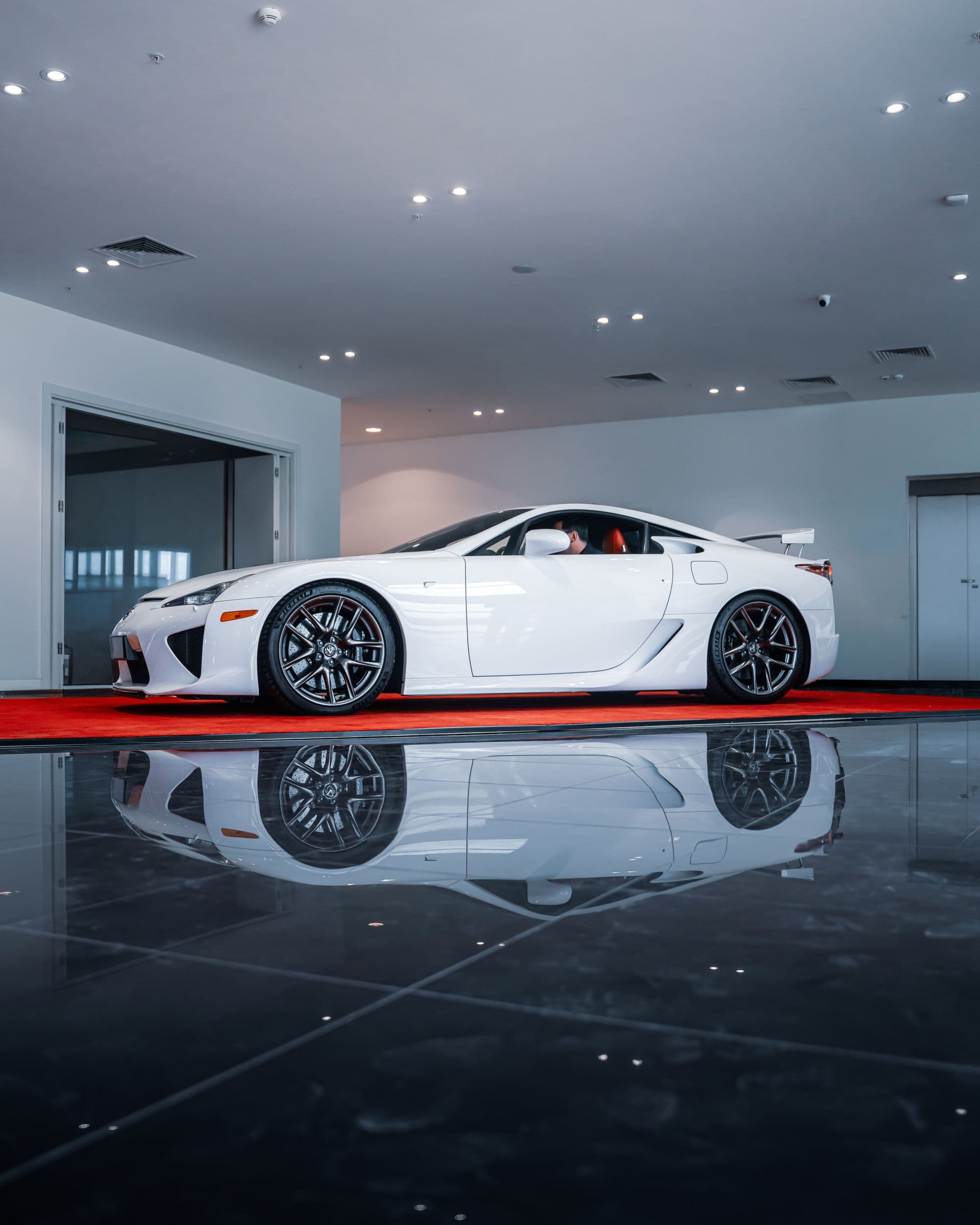 High-gloss epoxy floor reflecting a car under showroom lighting