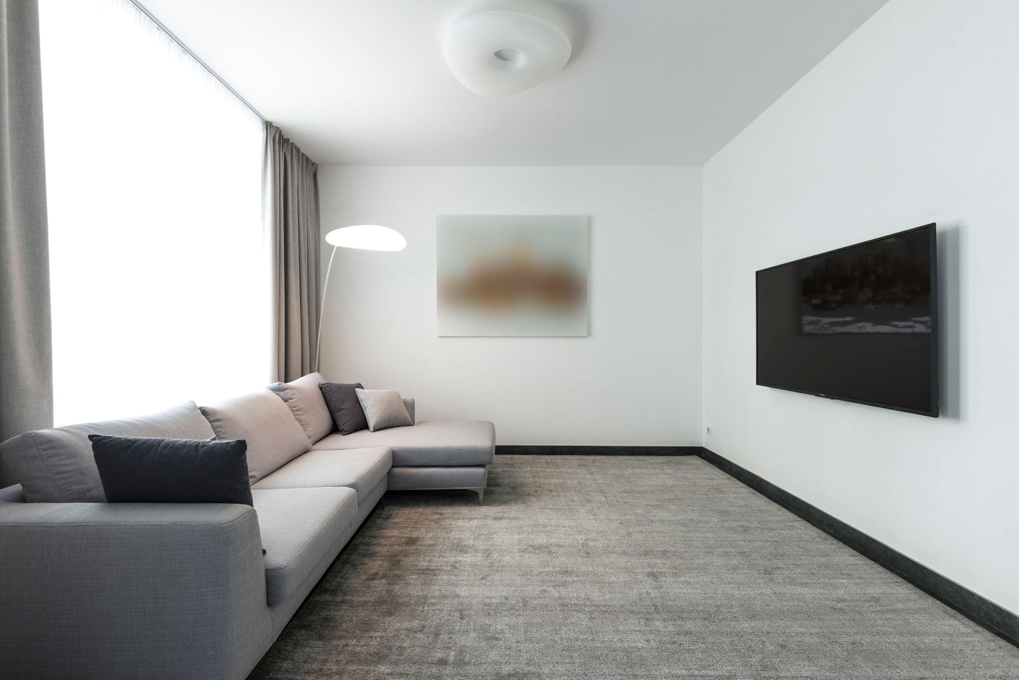 Wall-mounted television facing a grey sectional sofa