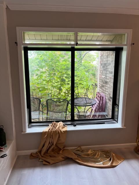 Black curtain rod mounted level above a wide window with curtains ready to hang