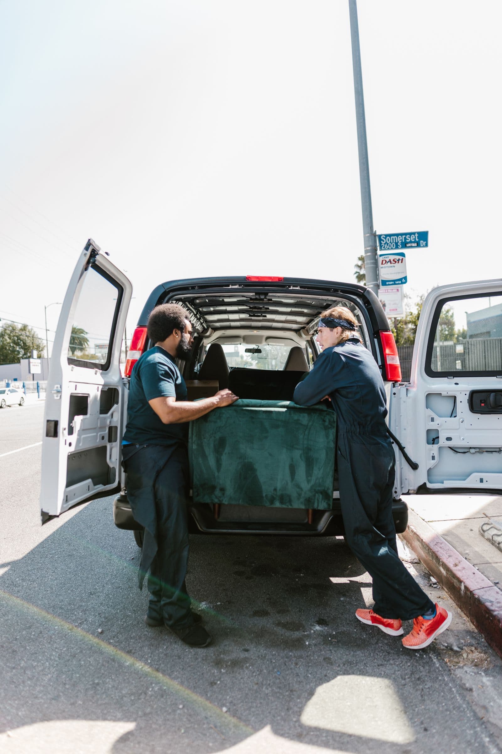Two movers loading a sofa into the back of a van