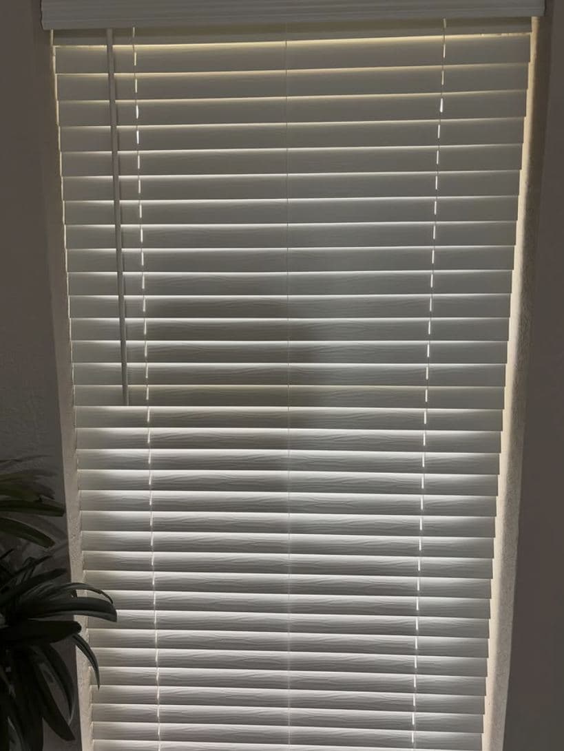 White window blinds mounted level across a tall window